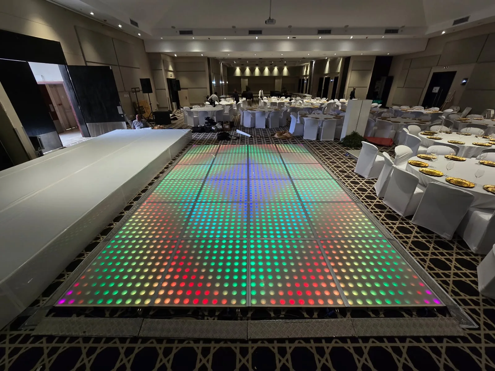 Colourful LED floor installed beside a stage in a hotel ballroom
